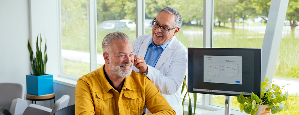 Image of middle aged man in an office visit with his male hearing care professional